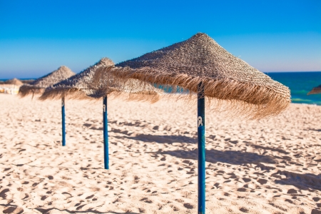 Straw umbrellas on empty tropical beach on the Atlantic coastの写真素材