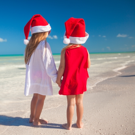 Little cute girls in Christmas hats on the exotic beachの写真素材