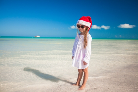 Little girl in red hat santa claus and sunglasses on the exotic beachの写真素材