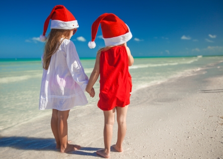 Little cute girls in Christmas hats on the exotic beachの写真素材