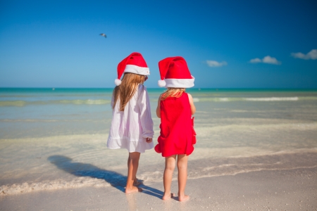 Little cute girls in Christmas hats on the exotic beachの写真素材