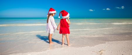 Little cute girls in Christmas hats on the exotic beachの写真素材