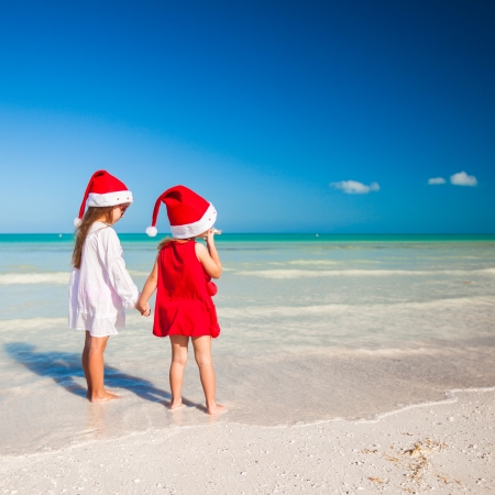 Rear view of Little cute girls in Christmas hats on the exotic beachの写真素材