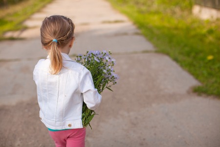 Little cute girl walking with a bouquet of flowersの写真素材