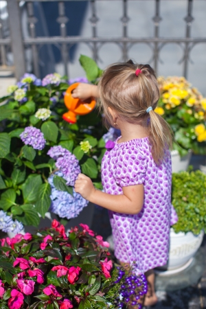 Little nice girl watering flowers with a watering canの写真素材