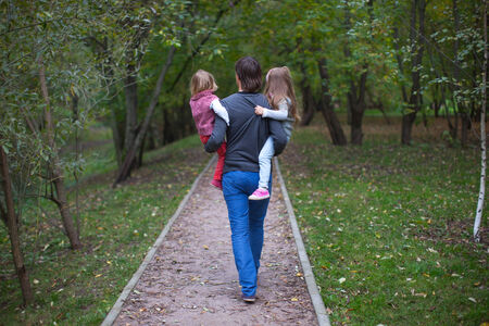 Back view of father and his two little daughters outdoorの写真素材