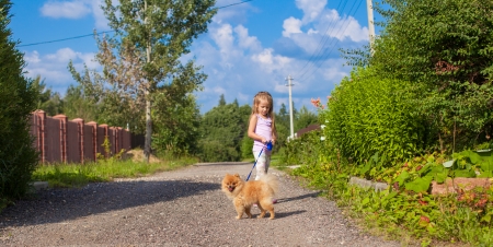 Little girl walking with her ââdog on a leashの写真素材