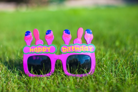 Red Happy Birthday Glasses on the grassの写真素材