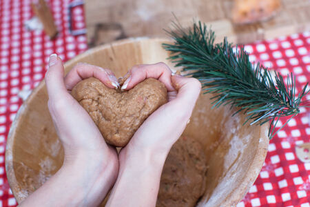 Woman holding gingerbread dough at hands in the shape of heart