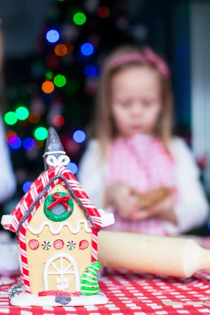 Gingerbread fairy house decorated by colorful candies on a background of little girl