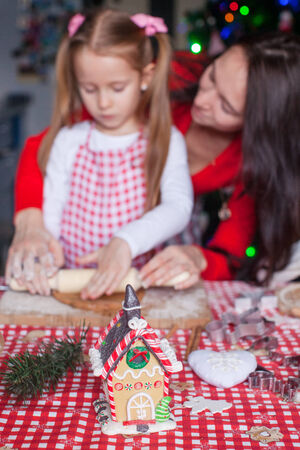 Gingerbread fairy house decorated by colorful candies on a background of happy familyの写真素材