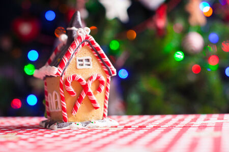 Gingerbread fairy house decorated with colorful candies on a background of bright Christmas tree with garlandの写真素材