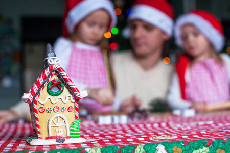 Gingerbread fairy house decorated by colorful candies on a background of happy familyの写真素材
