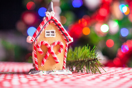 Close-up Gingerbread fairy house decorated by colorful candies on a background of bright Christmas tree with garlandの写真素材