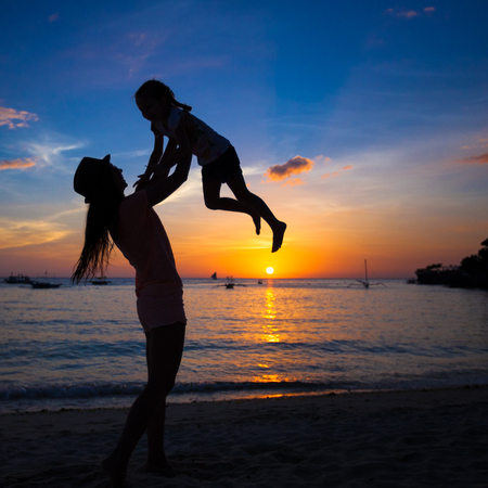 Silhouette of mother and little daughter playing on the beach of Boracay, Philippinesの写真素材