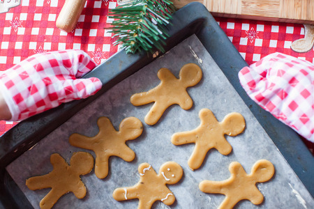 Raw gingerbread men with glaze on a baking sheetの写真素材