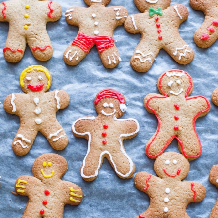 Raw gingerbread men with glaze on a baking sheet