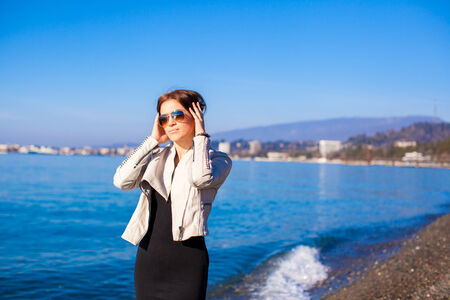 Beautiful young woman walking on the beach in winter sunny day aloneの写真素材