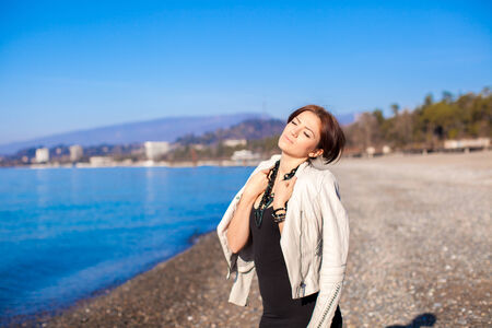 Beautiful young woman relax on the beach in winter sunny day aloneの写真素材