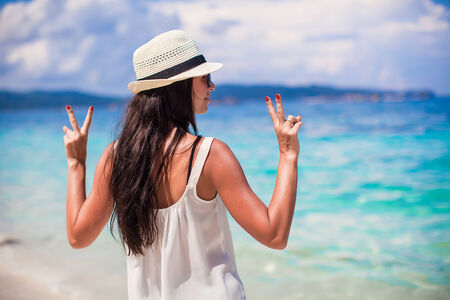 Young woman in hat with raised hands at perfect beachの写真素材