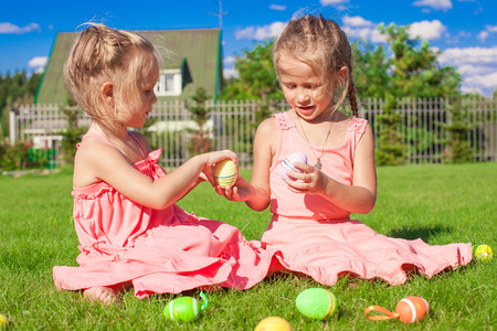 Adorable little girls playing with Easter Eggs on green grassの写真素材