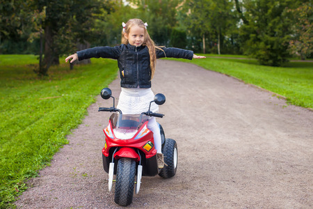 Adorable little girl having fun on her toy motorcycle