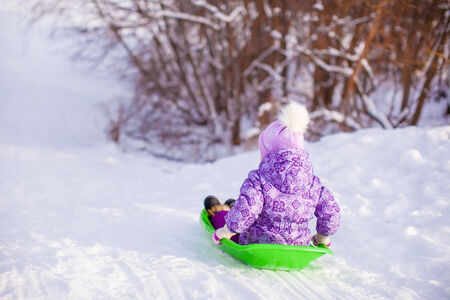 Little cute girl pulls a sled in warm winter dayの写真素材
