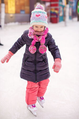 Adorable happy little girl enjoying skating at the ice-rinkの写真素材