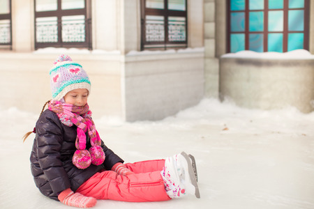 Little adorable girl sitting on the ice with skates after the fallの写真素材