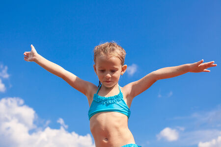 Adorable little girl spread her arms background of the blue skyの写真素材