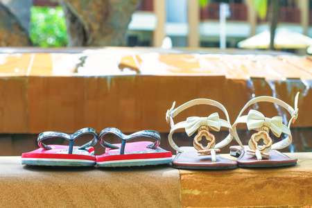 Close-up of male and female flip flops near poolsideの写真素材