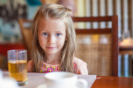Fashion little girl having breakfast at resort restaurantの写真素材