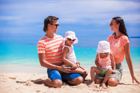 Young beautiful family of four enjoyed relaxing on the beachの写真素材