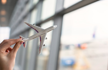 Close up hand holding an airplane model background the airportの写真素材