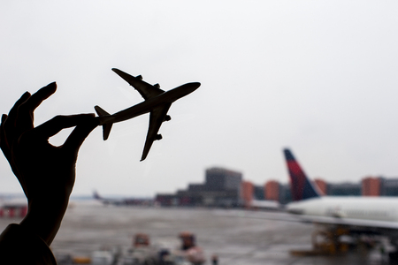 Close up hand holding an airplane model background the airportの写真素材