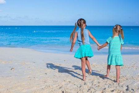 Back view of two sisters looking at the sea on the white beachの写真素材