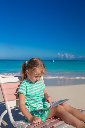 Little adorable girl with laptop on the beachの写真素材