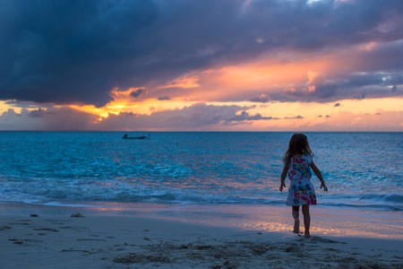 Little girl walking in the sunset on a tropical beachの写真素材