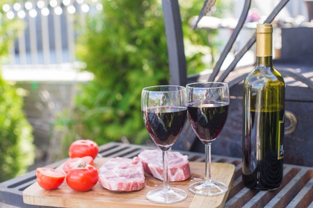 Fresh meat, vegetables and wine on a picnic outdoorsの写真素材