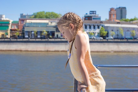 Little girl on the deck of a ship sailing in the big cityの写真素材