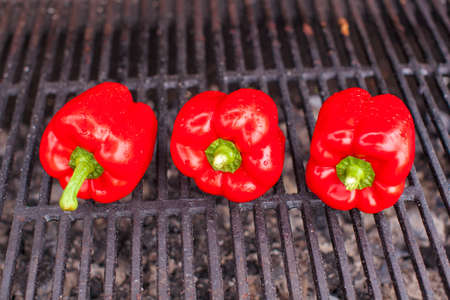 Three Red peppers on a outdoor barbecueの写真素材