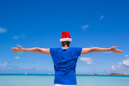 Back view of young man in santa hat on tropical carribean beachの写真素材