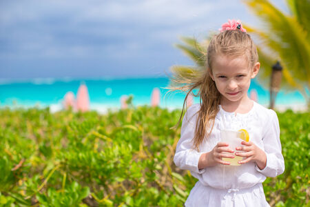 Adorable little girl drinking juice at beach cafeの写真素材