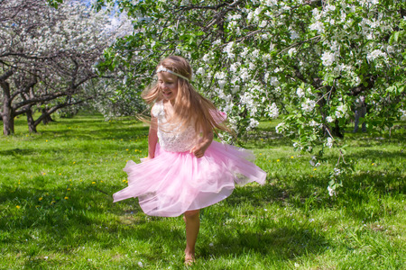 Little adorable girls with butterfly wings under blossoming apple treeの写真素材