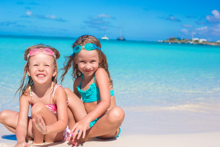 Little cute girls in glasses for swimming playing in the sand on summer vacationの写真素材