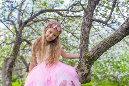 Little adorable girl with butterfly wings under blossoming apple treeの写真素材