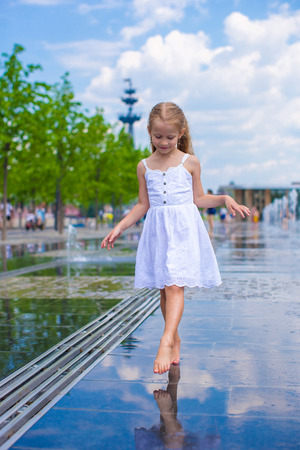Adorable little girl playing in street fountainの写真素材