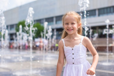 Adorable little girl playing in street fountainの写真素材
