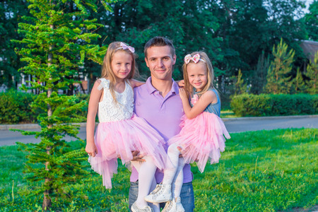 Young dad and his adorable daughters having fun outdoorの写真素材