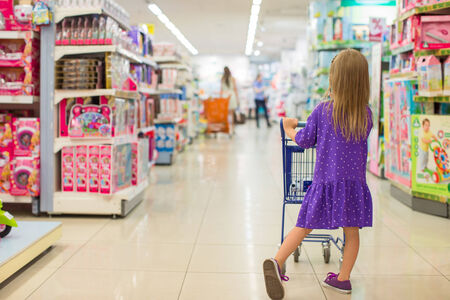 Back view of fashion girl with trolley in shopping centerの写真素材